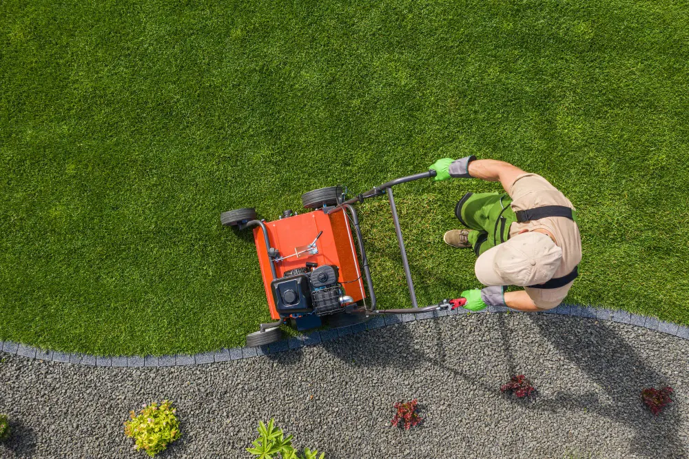 A man mowing grass with a lawn mower.